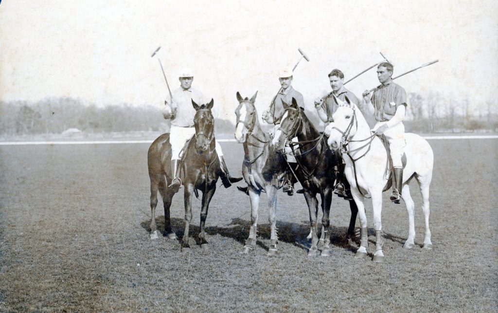 Four polo riders on horses.