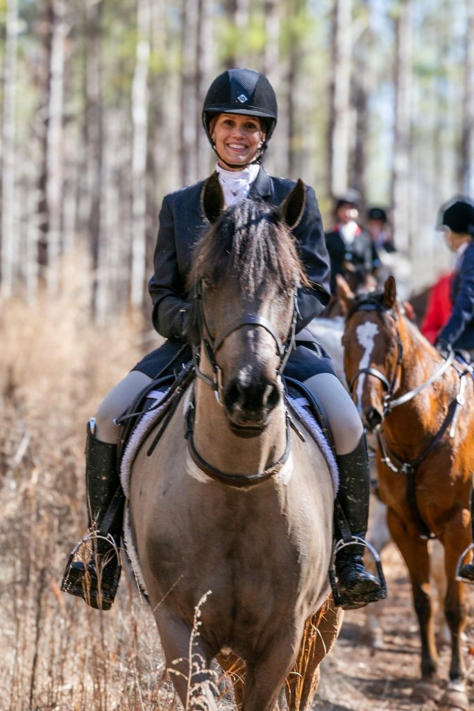 Woman in formal hunt attire on horse.