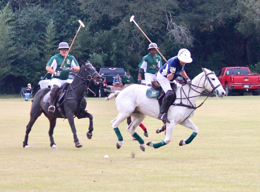 Polo players galloping in game.