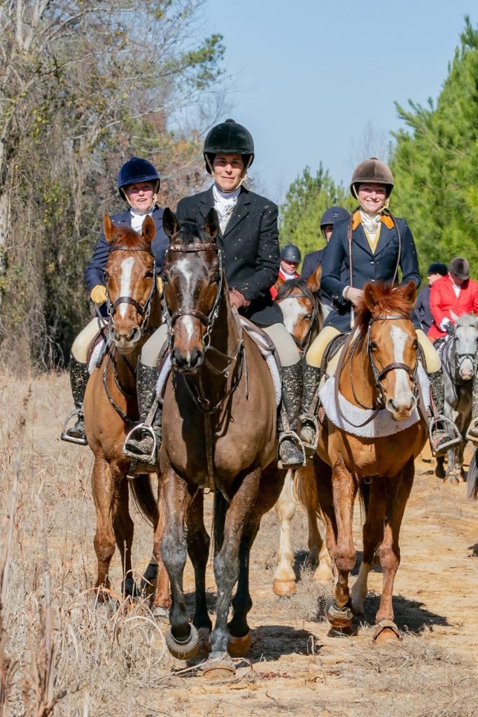 Group of hunt riders walking on path.